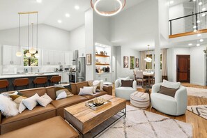 A spacious living area with a large sofa, a coffee table, and a dining area with a table and chairs.