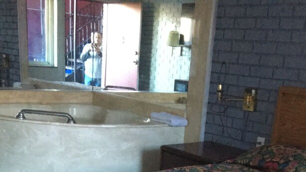 A room with a bed, a window, a sink, and a mirror. - Dorchester Motel (Redford)
