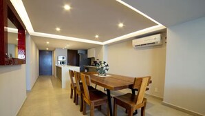 A modern kitchen with a central island, a dining area with a wooden table and chairs, and recessed ceiling lighting. - Luxury Oceanfront Condo with WiFi, Pool, and Fitness Room in Puerto Vallarta (Puerto Vallarta)