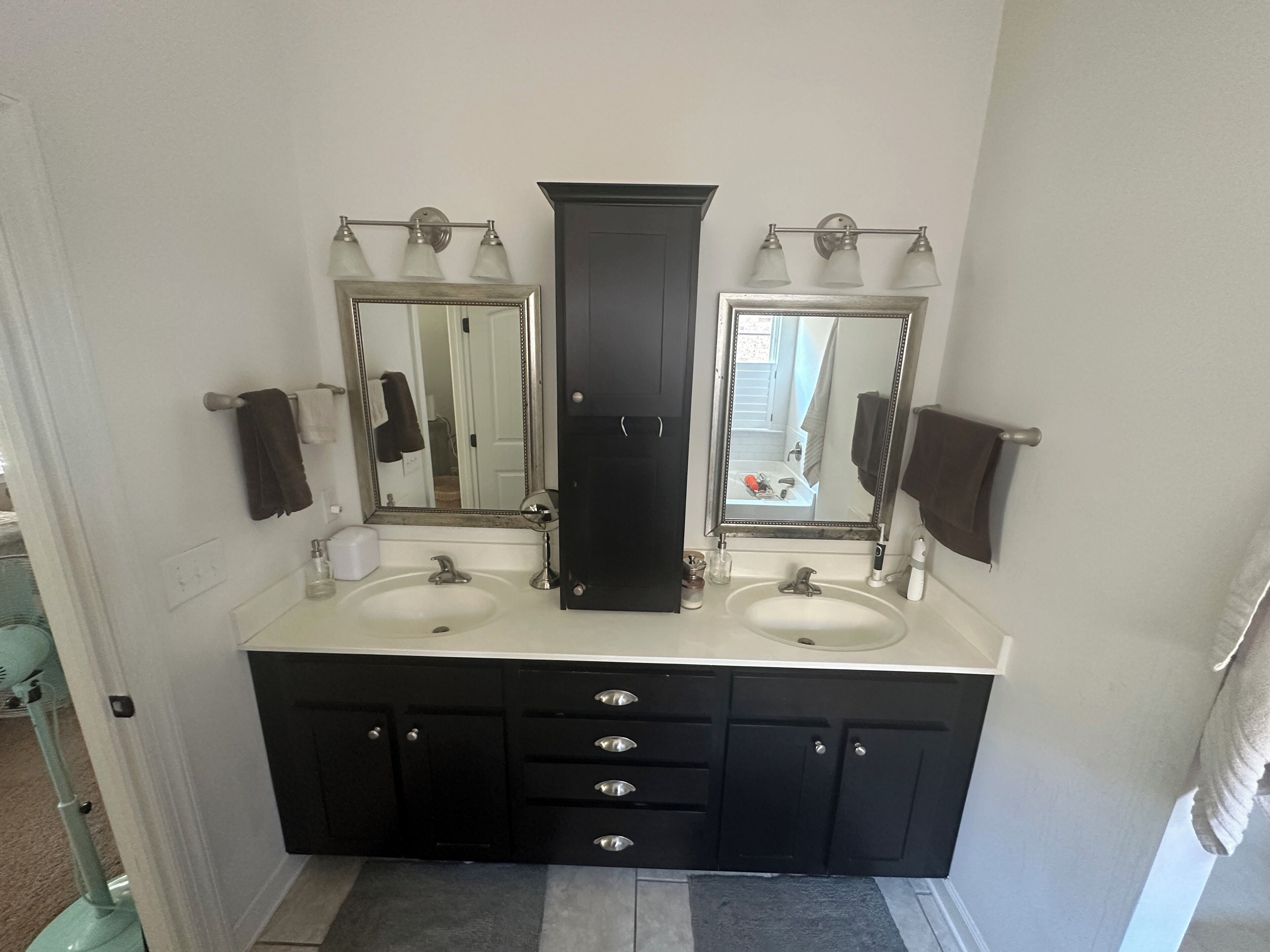 A bathroom with two sinks, a large mirror, a cabinet, and a towel rack.
