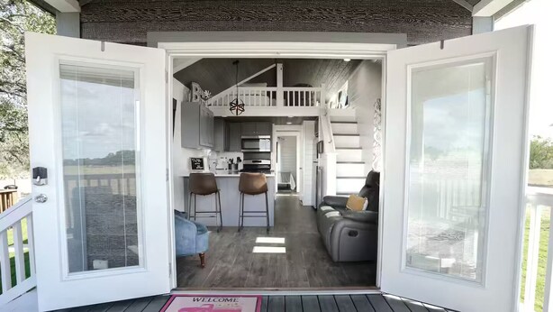 Une maison moderne dotée d’un vaste espace de vie à aire ouverte, d’une cuisine et d’un balcon.