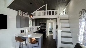 Une cuisine moderne dotée d’un îlot central, de tabourets de bar et d’un escalier menant à un niveau supérieur.