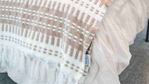 Un lit recouvert d’une couverture blanche et beige, un oreiller blanc et un sol recouvert d’un tapis gris.