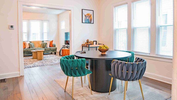 Un coin repas moderne avec une table ronde, deux chaises et un saladier rempli de fruits.