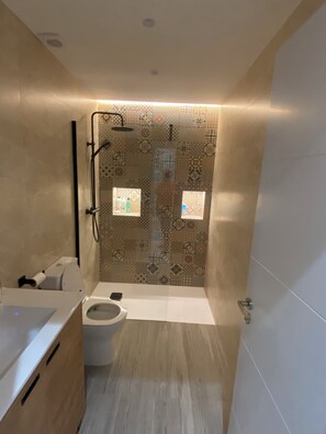 Une salle de bain moderne équipée d’une douche, de toilettes et d’un lavabo.