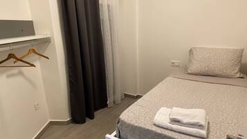Un dormitorio con cama, mesita de noche, toalla colgada, armario y cortina de ducha.