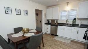 A modern kitchen with white cabinets, a stainless steel dishwasher, and a black countertop.
