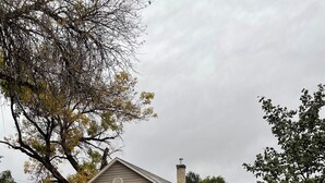 A single-story house with a front porch, a chimney, and a small front yard with scattered leaves.