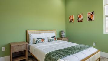 A bedroom with a bed, nightstands, and artwork on the wall.