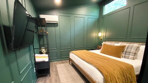 A bedroom with a bed, a TV mounted on the wall, a bedside table, and a window.