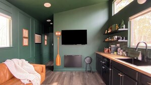 A compact kitchen with a wooden countertop, a built-in dishwasher, and a window with a view of trees.