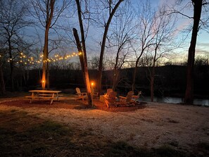 Un campamento con mesas y sillas de picnic, rodeado de árboles y un lago.