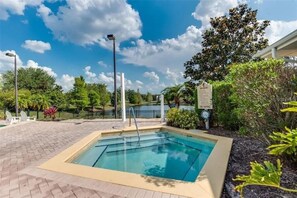 A rectangular pool with a tiled deck, surrounded by greenery and a clear sky. - 3 bed - Private Oasis - Completley Immaculate (Kissimmee)