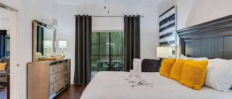 A hotel room with a large bed, a dresser, a mirror, and a balcony with a table and chairs.