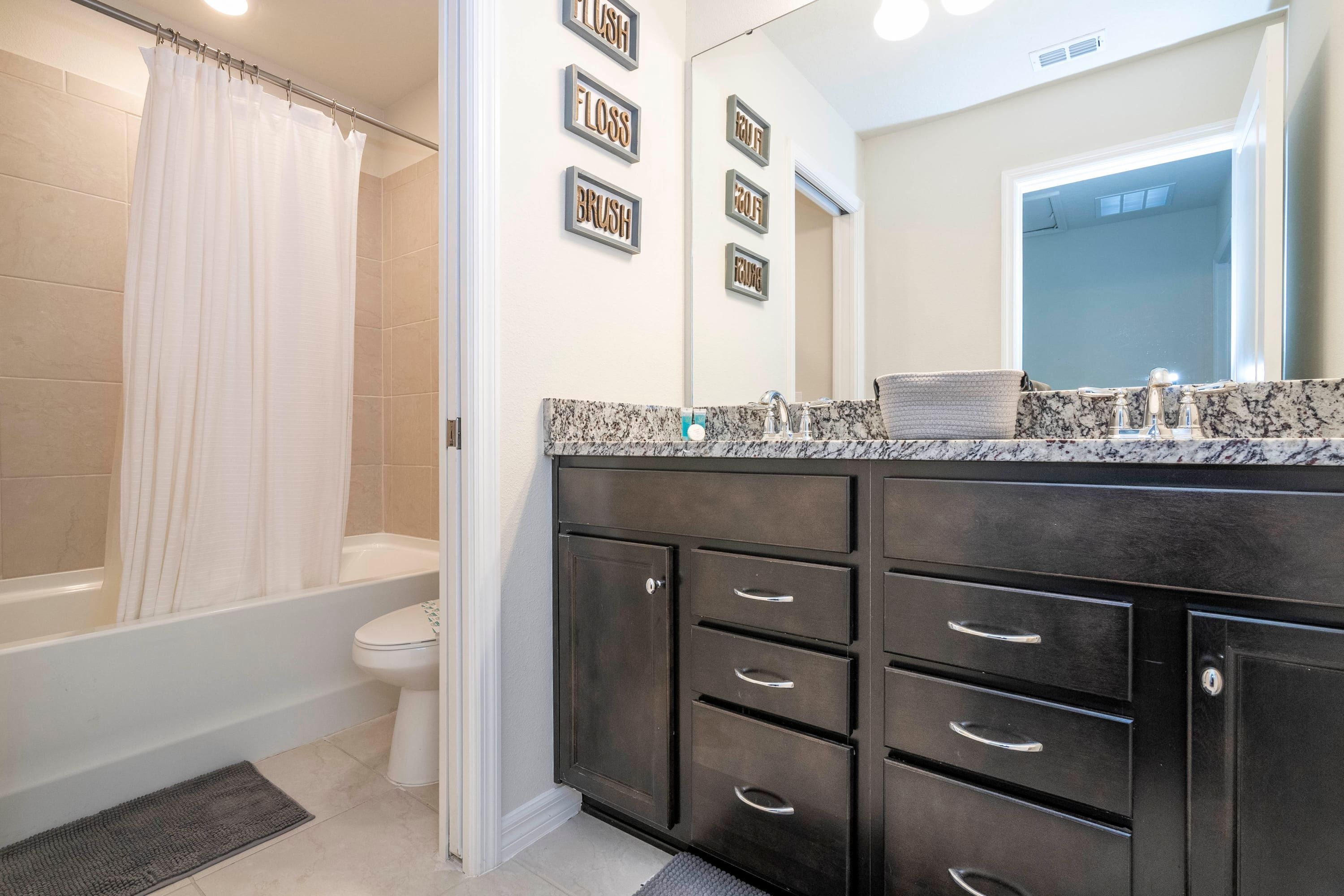 A bathroom with a bathtub, toilet, and vanity with drawers.