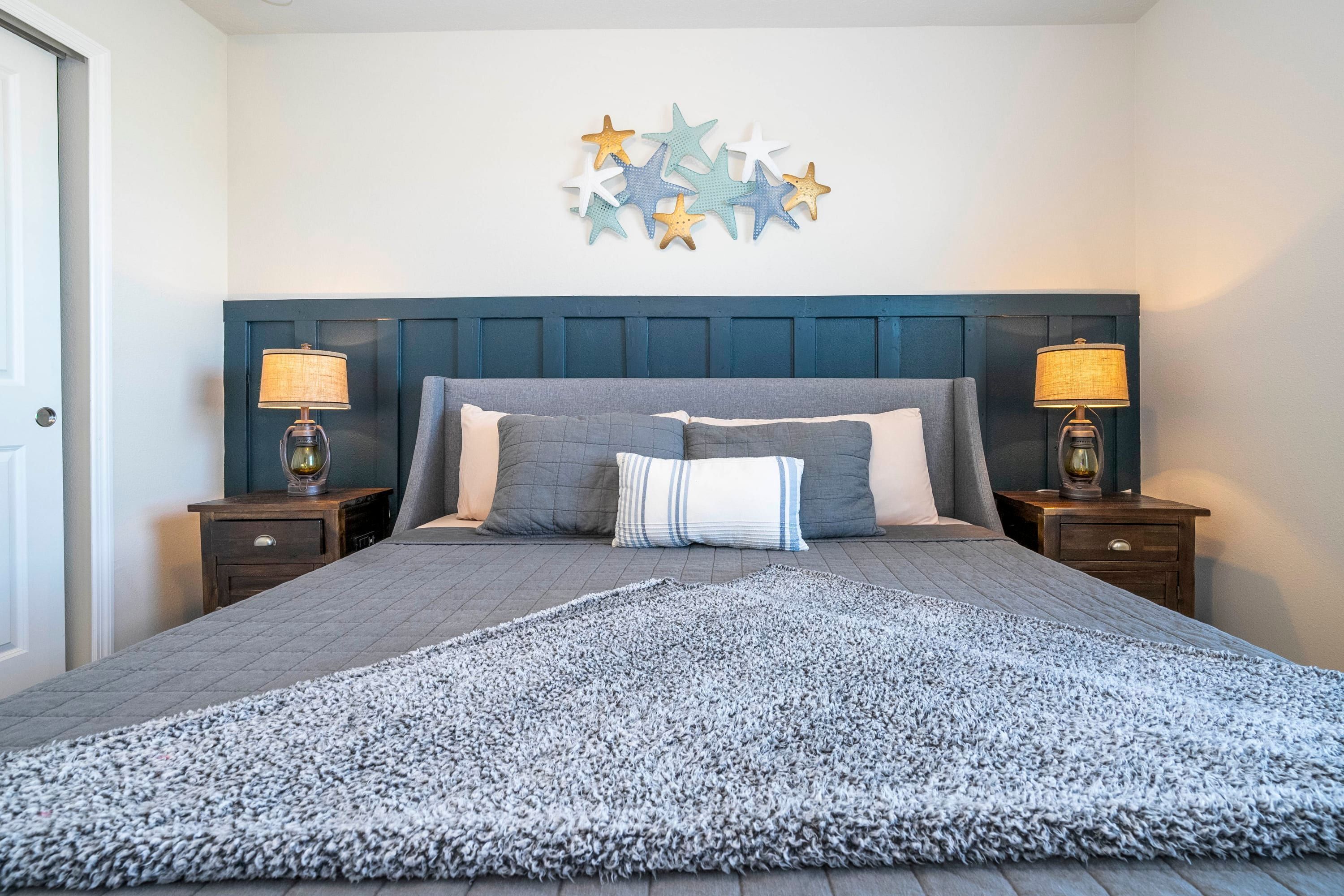 A bedroom with a bed, two bedside tables, a wall decoration, and a rug.