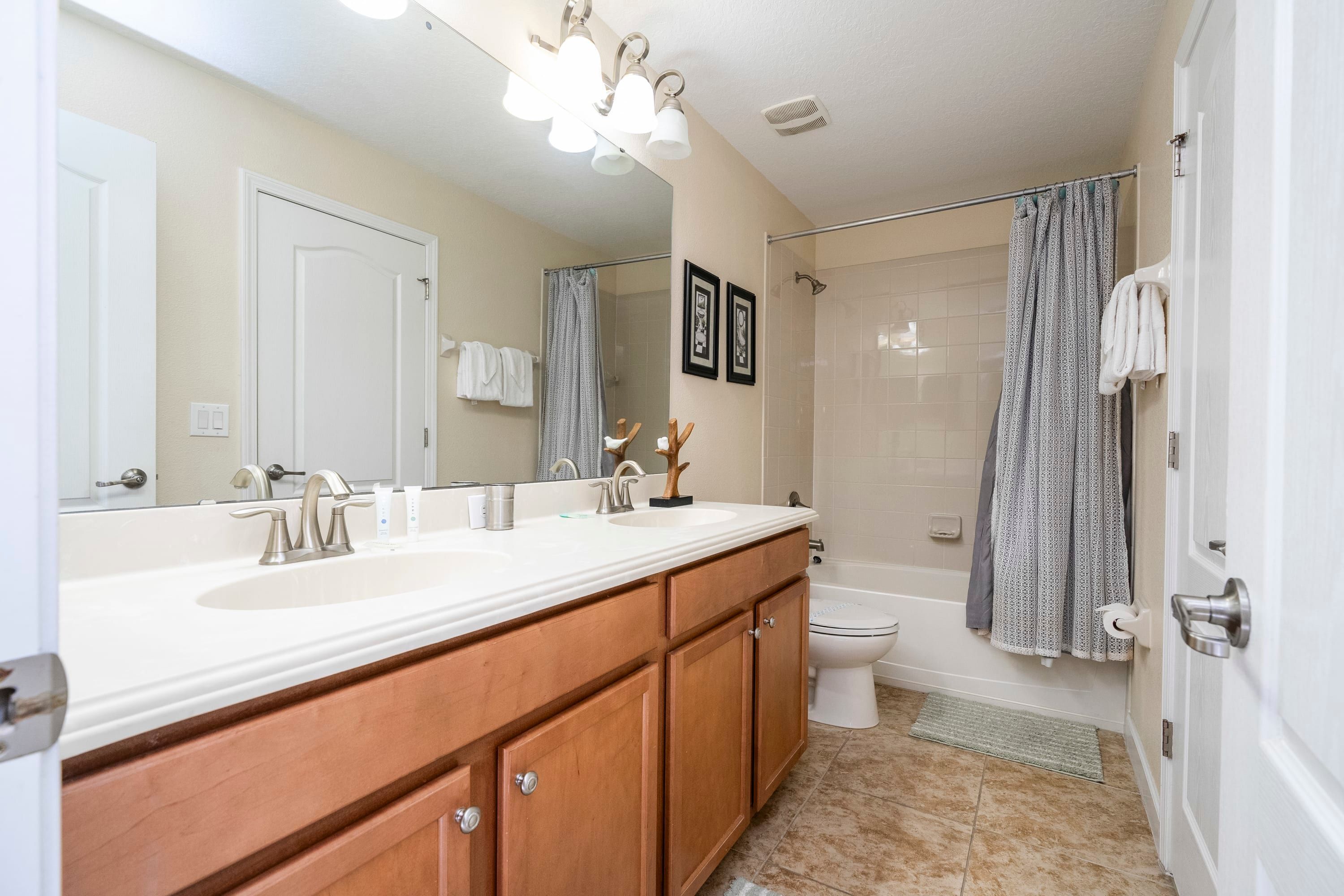 A bathroom with a double sink vanity, a large mirror, a shower with a glass door, and a toilet.