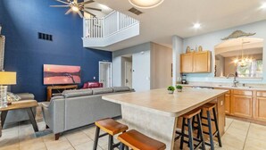 Una cocina moderna con una isla central, taburetes de bar y un ventilador de techo.