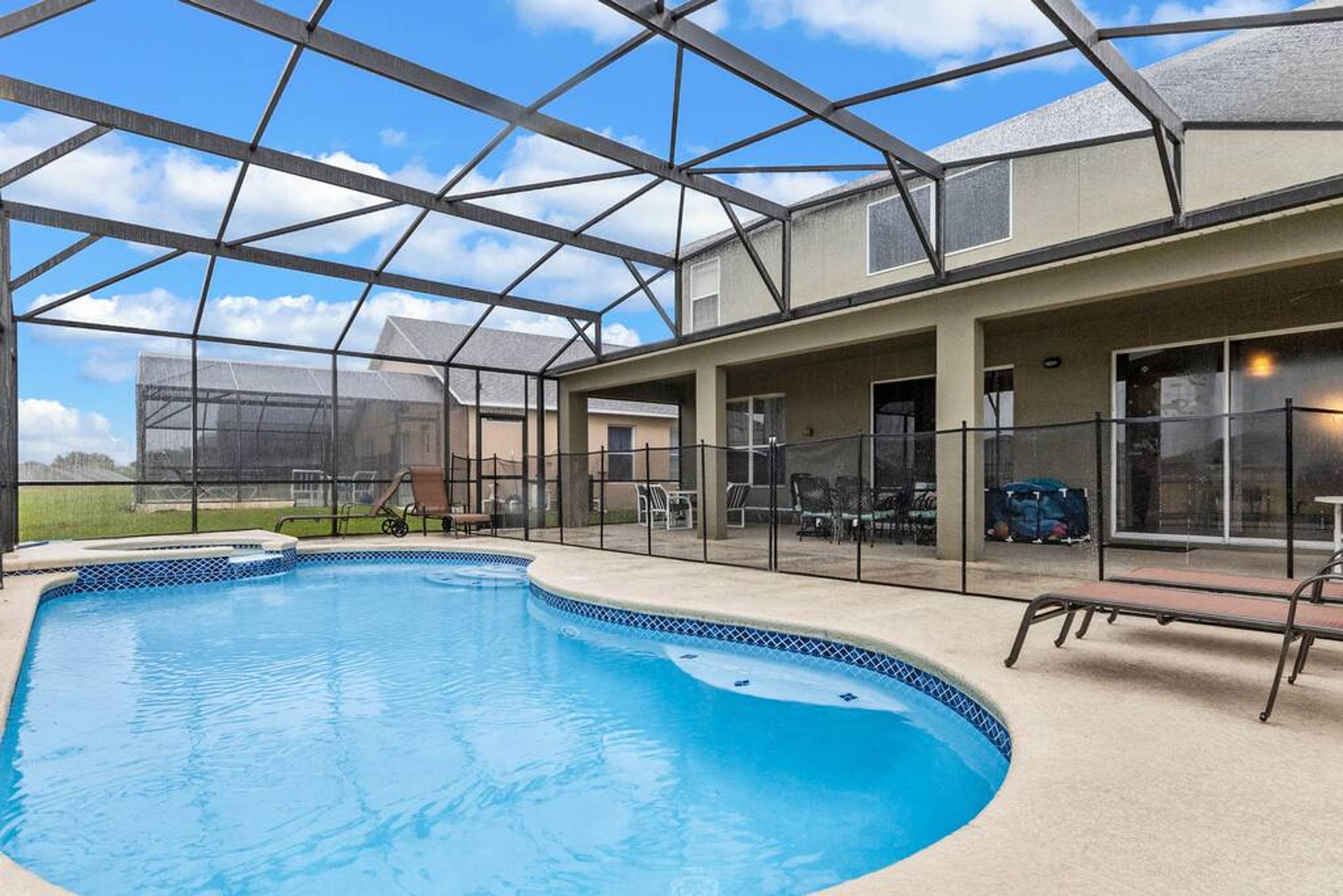 Une piscine couverte dotée d’une structure de toit transparente, entourée d’une clôture et équipée de chaises longues.