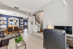 A spacious living area with a sofa, a coffee table, and a TV. There is a staircase leading to another level. - Welcome Home Perfect for Business Travel and Snow Birds (Kissimmee)