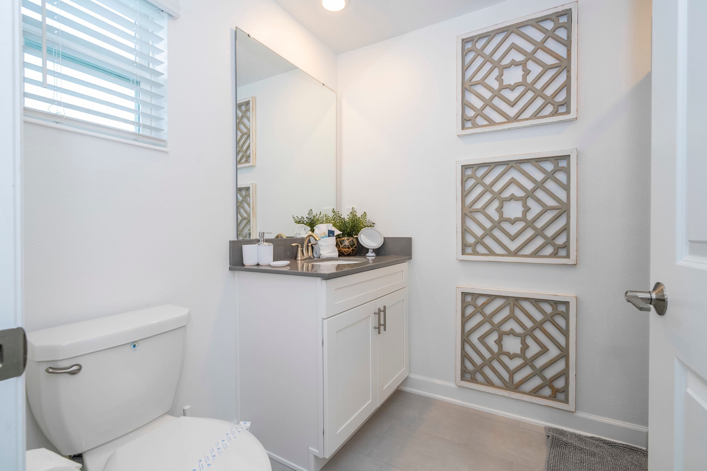 A bathroom with a toilet, a sink with a mirror, and decorative wall panels.
