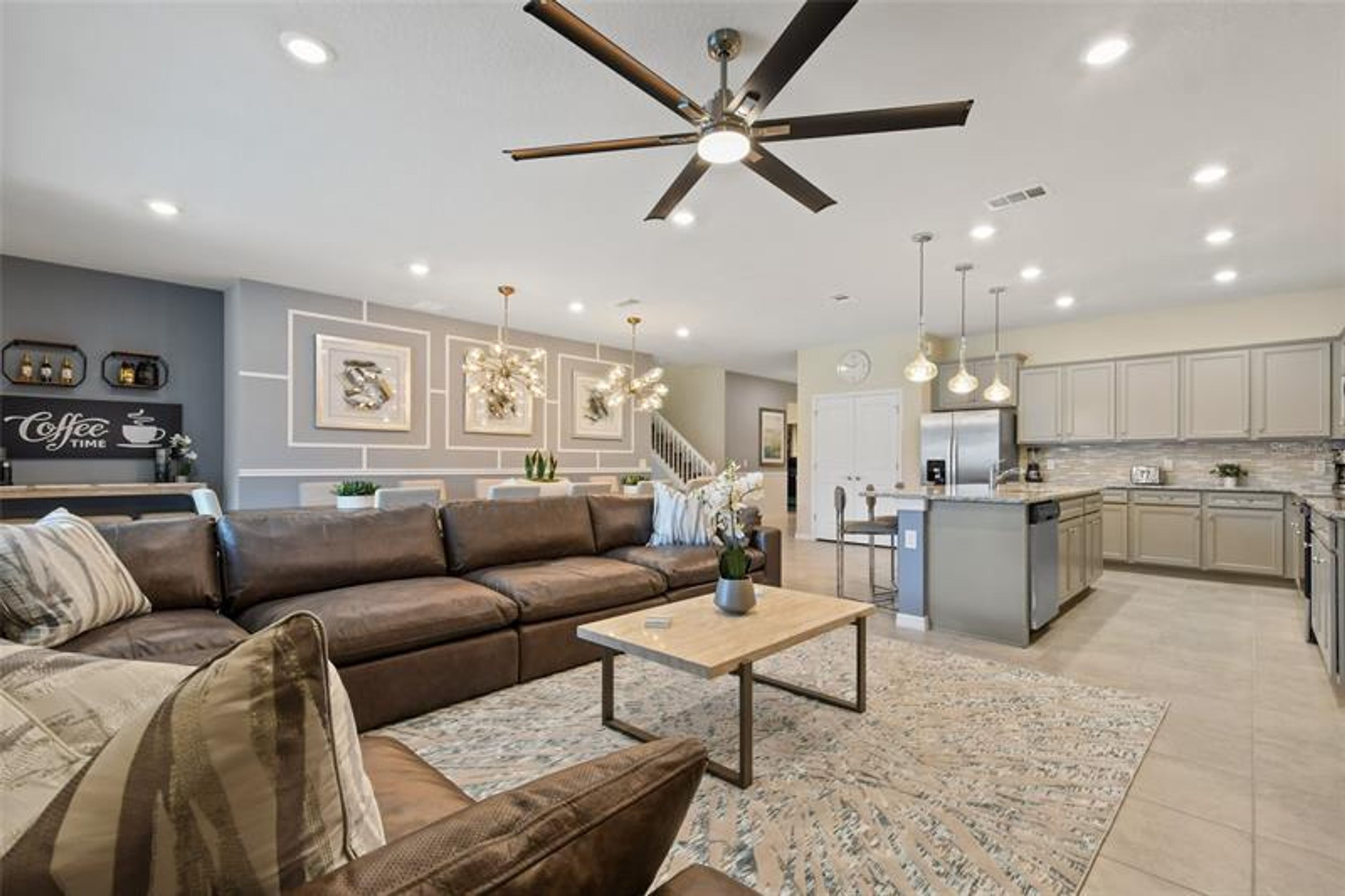 A modern living room with a brown leather sofa, a wooden coffee table, and a ceiling fan.