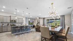 A spacious kitchen with a central island, bar stools, and pendant lighting. - Unrivaled Amenities Unforgettable Comfort Await (Davenport)