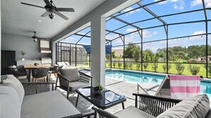 A modern outdoor living area with a pool, seating, and a ceiling fan. - Unrivaled Amenities Unforgettable Comfort Await (Davenport)