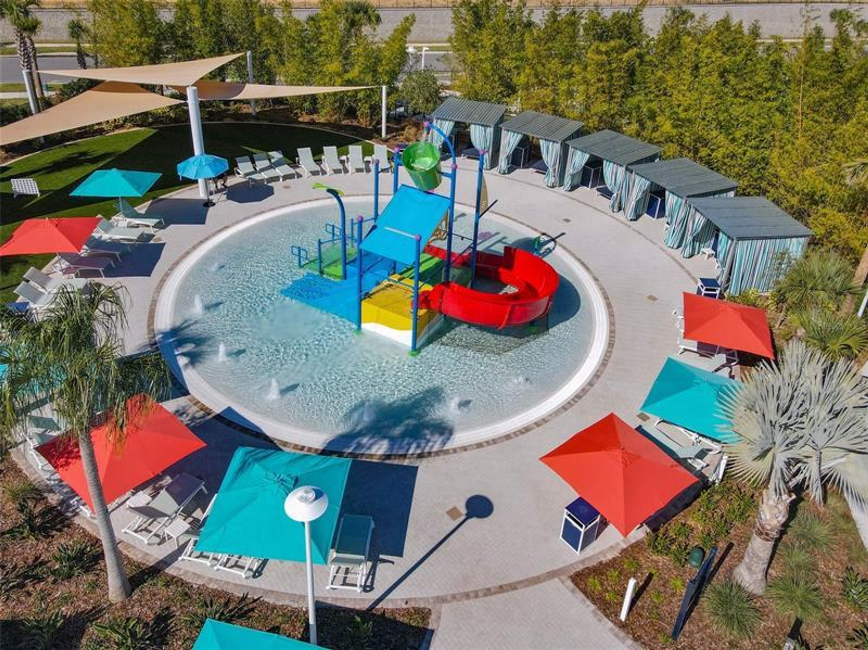 A water park with a circular pool, slides, and sun loungers.
