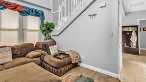 A living room with a brown sectional sofa, a staircase, and a plant. - Beautiful Sunsets at 3BR Villa in Reno (Reno)