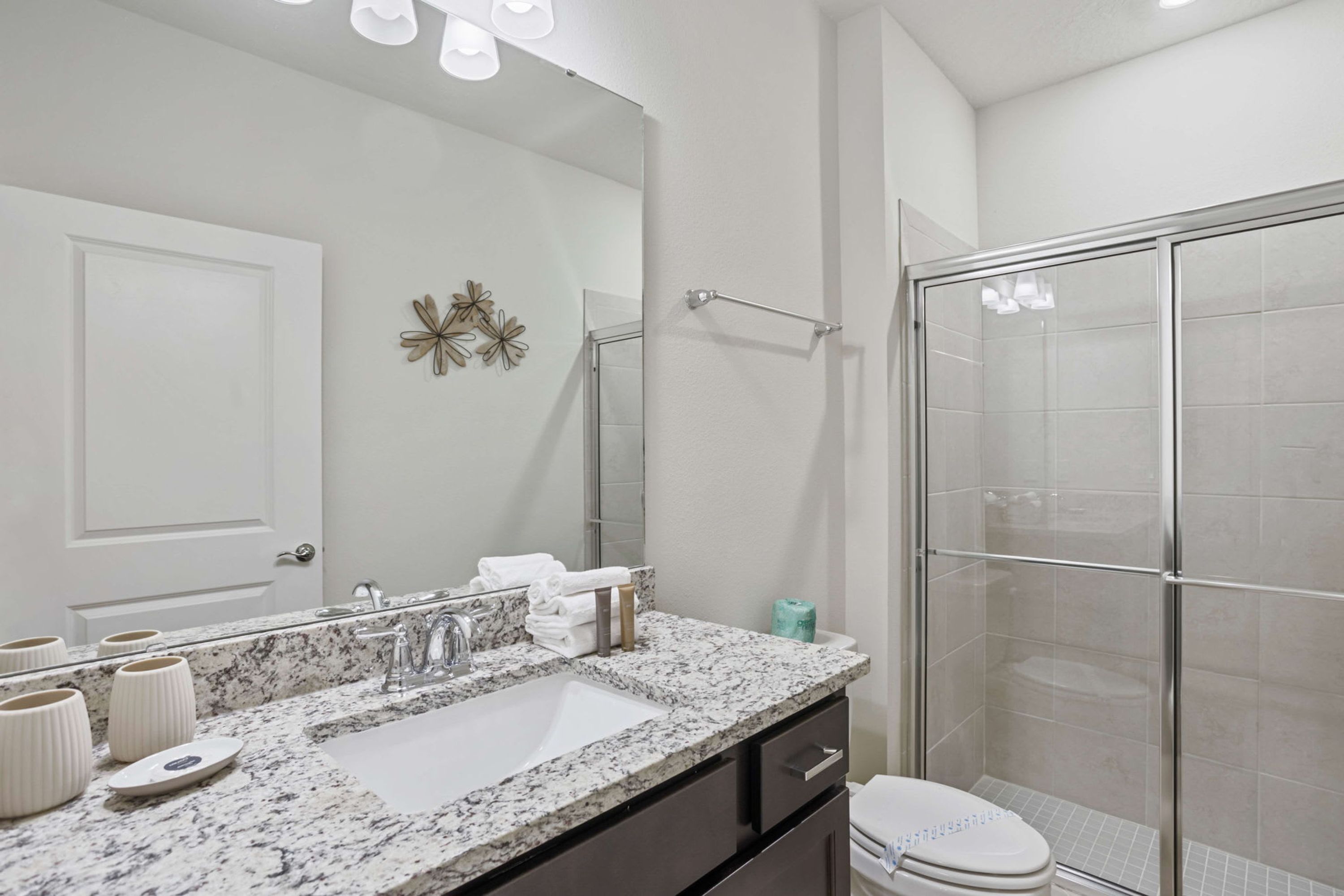 A modern bathroom with a large mirror, a sink, and a shower.