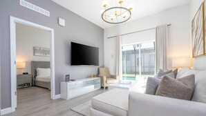 Un salon moderne doté d’un téléviseur à écran plat, d’un canapé, d’une table basse en verre et offrant une vue sur un balcon.