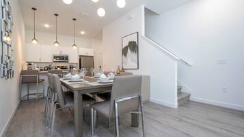 A modern kitchen with white cabinets, a microwave, and a dining area with a table set for four.