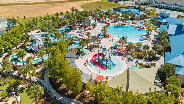 An aerial view of a resort with multiple swimming pools, water slides, and lounge areas surrounded by palm trees. - Free Pool Heat if you Stay in the Month of November (Davenport)