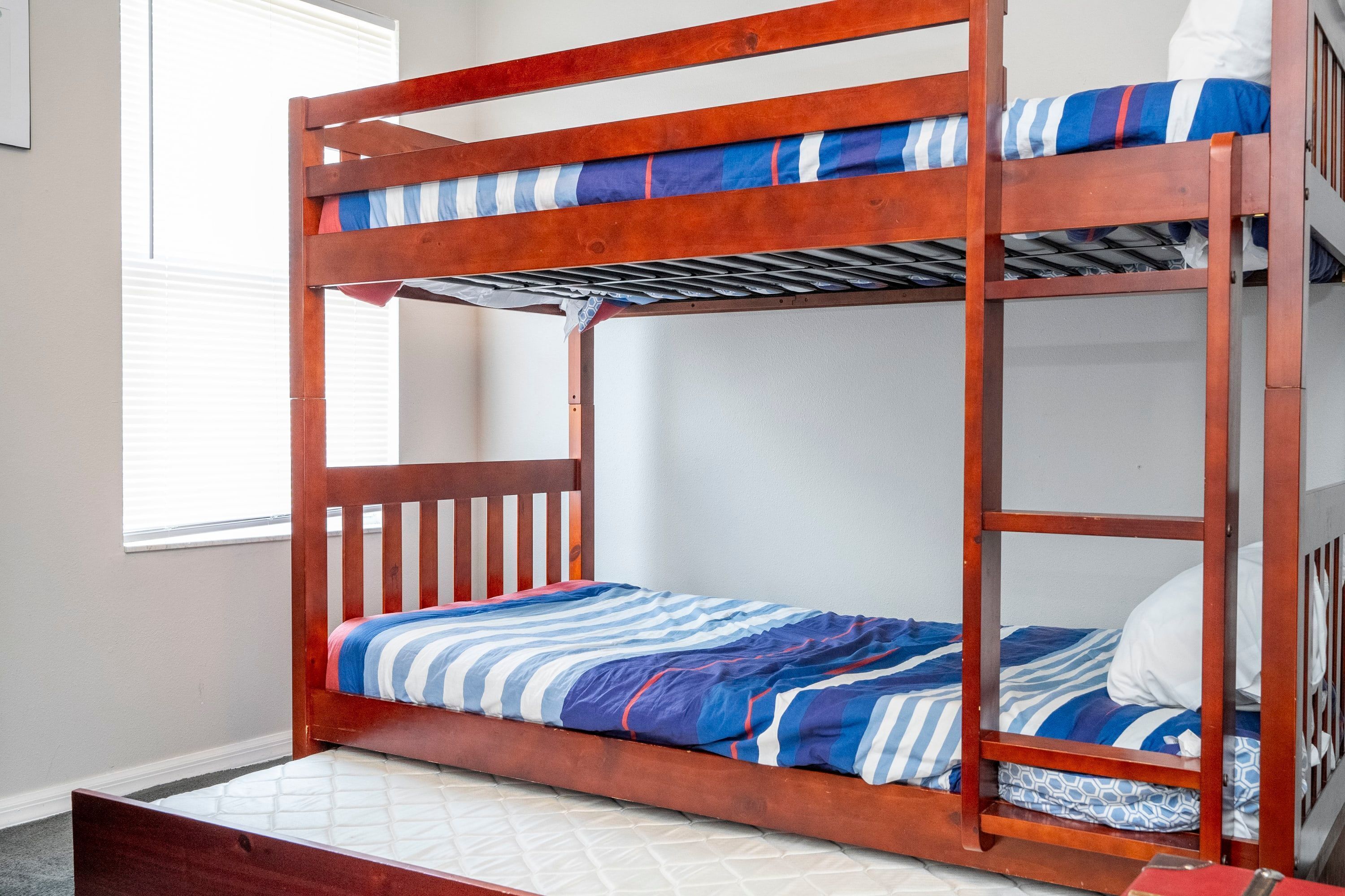A bunk bed with a wooden frame and blue-striped bedding.
