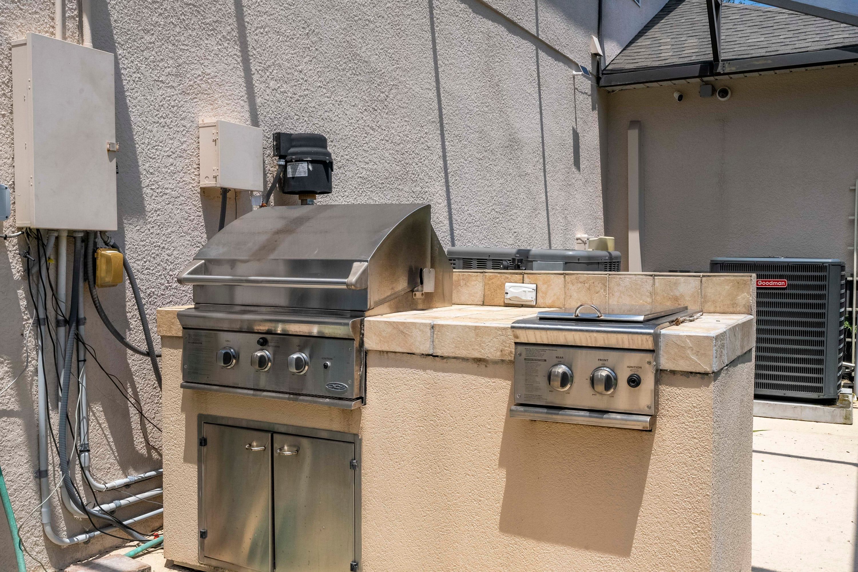 An outdoor kitchen with a gas grill, a built-in oven, and a portable range.