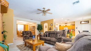 A spacious living room with a ceiling fan, a sofa set, and a coffee table. - Enjoy Your own Water Slide and Free Pool Heat if you Stay in November (Kissimmee)
