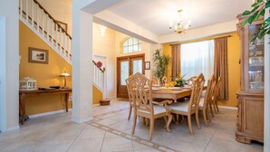 A dining area with a wooden table and chairs, a staircase, and a chandelier. - Enjoy Your own Water Slide and Free Pool Heat if you Stay in November (Kissimmee)