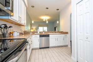 A modern kitchen with white cabinets, stainless steel appliances, and a granite countertop. - Tropical Oasis 2BD Near Disney Pure Relax (Kissimmee)