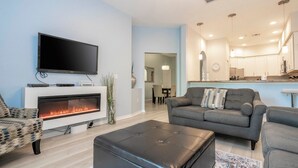 Una sala de estar moderna con televisor de pantalla plana, chimenea y sofá.