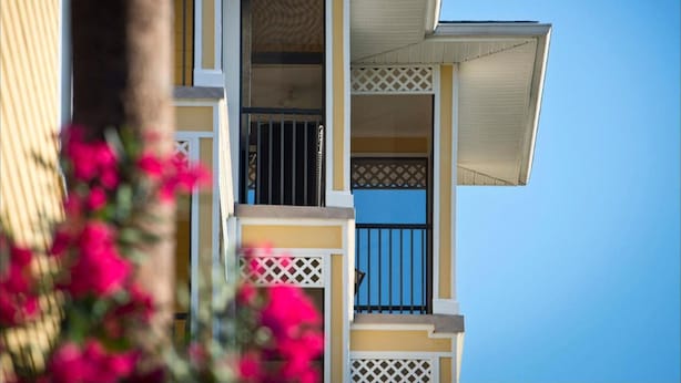 Un edificio de varios pisos con balcones, un diseño de ventana con celosías y un cielo azul despejado al fondo.