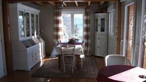 A dining area with a table and chairs, a cabinet, and a view through a window.