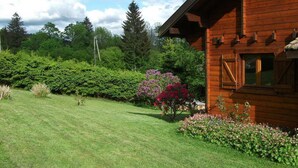 A wooden cabin with a well-maintained lawn and flowering plants.