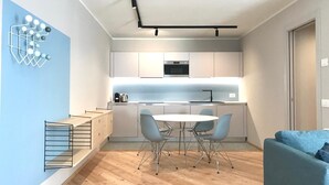 Eine moderne Küche mit weißen Schränken, einem eingebauten Ofen und einem Essbereich mit einem runden Tisch und Stühlen.