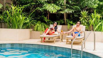 Área de piscina com espreguiçadeiras e piscina.