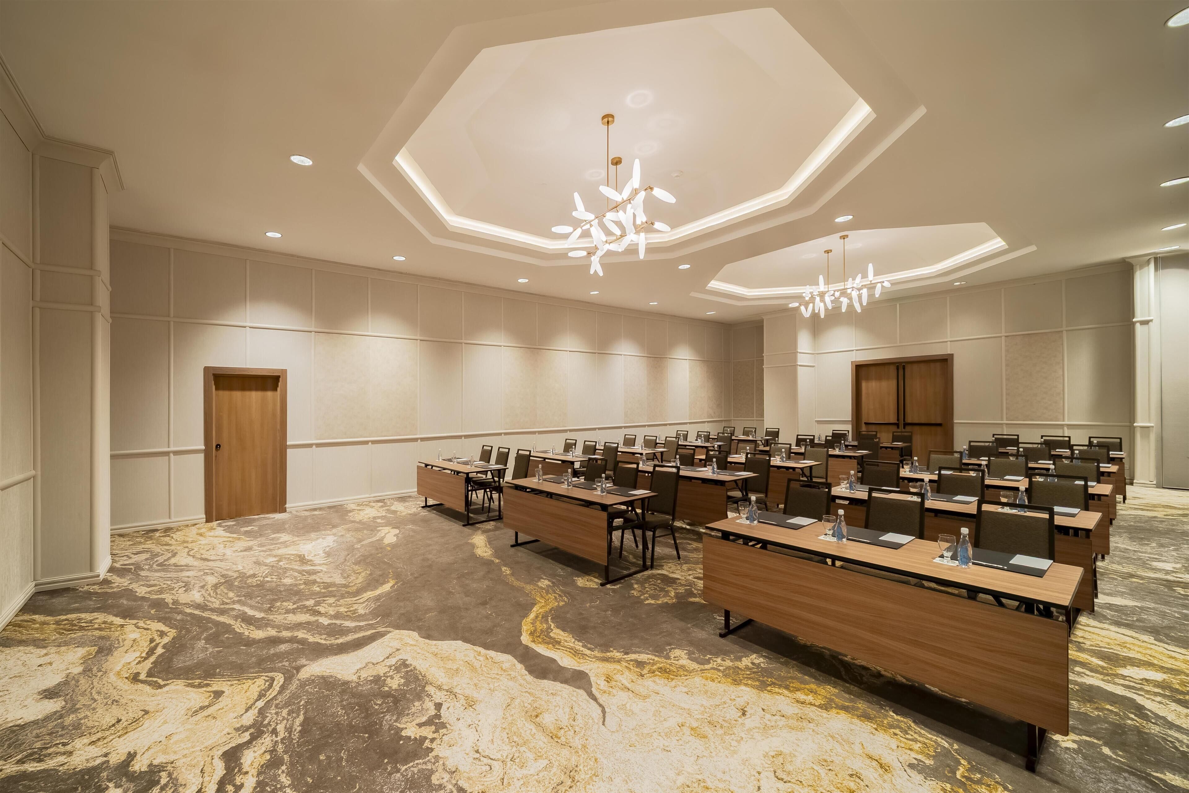 A conference room with long tables, chairs, and a modern chandelier.