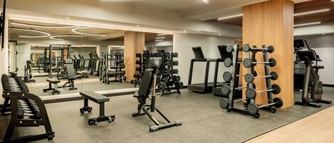 A modern gym with various exercise equipment, including treadmills, weight machines, and free weights.