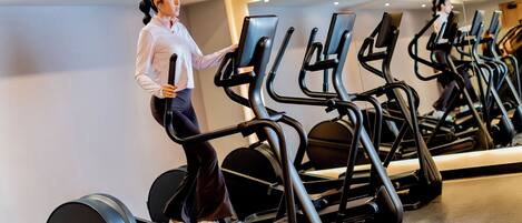 Un gimnasio con varias cintas de correr dispuestas en filas.