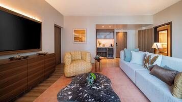A modern living room with a flat-screen TV, a sofa, a patterned armchair, and a coffee table with a vase.
