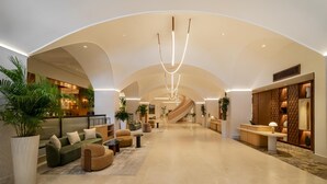 A spacious lobby with a curved ceiling, a central staircase, and a reception desk. - Hyatt Regency Panama City (Panama City)